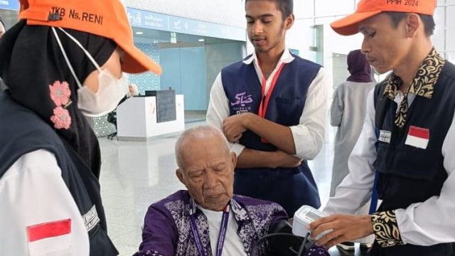 Petugas kesehatan memeriksa suhu tubuh jemaah haji yang baru tiba di bandara sebagai langkah deteksi dini penyebaran Covid-19.